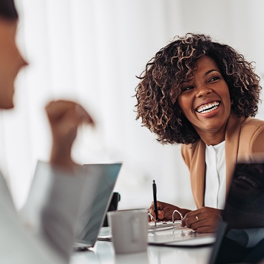 Woman smiling while taking notes during meeting