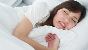 a woman experiencing bruxism while in bed