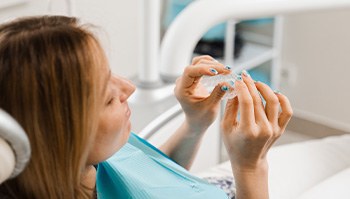 Patient holding clear aligner in treatment chair