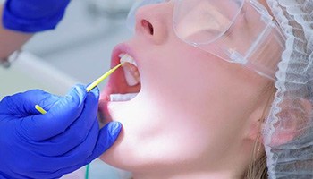Dental team member applying fluoride to a patient's teeth in Brick