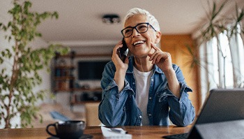 Woman with black glasses smiling while talking on phone