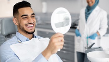 Man smiling at reflection in mirror in treatment chair
