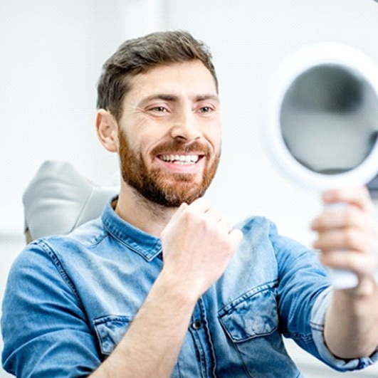 dental patient admiring smile in mirror after dental bonding in Brick Township