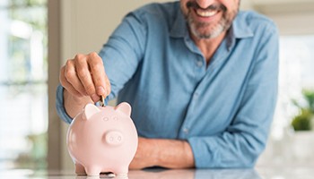 Man adding to piggy bank to make emergency dental care in Brick Township more affordable