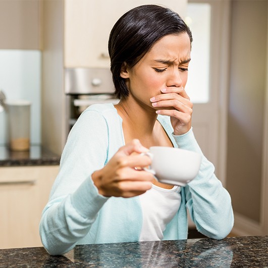 Grimacing woman in need of tooth extraction covering her mouth