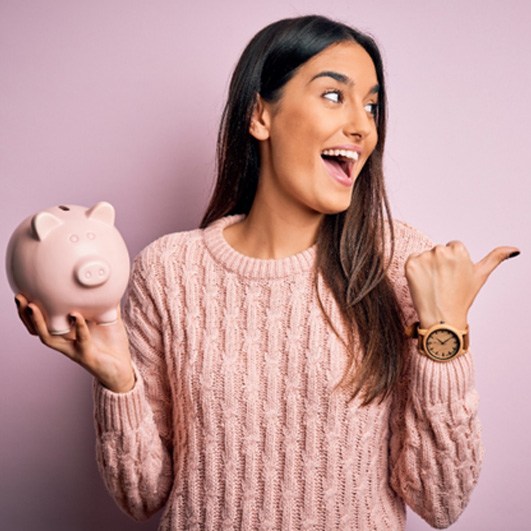 a woman smiling and holding a piggy bank