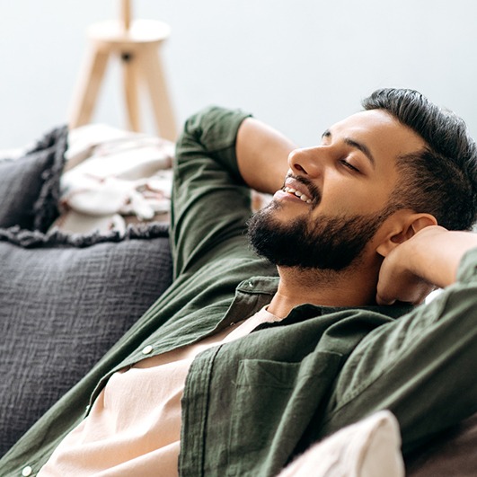 Man relaxing at home following tooth extraction appointment