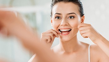 Woman practicing dental implant care in Brick Township by flossing