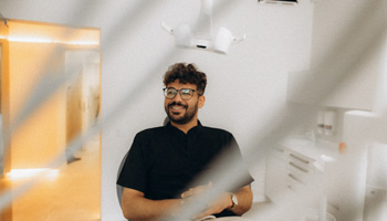 Patient with black glasses smiling in treatment chair