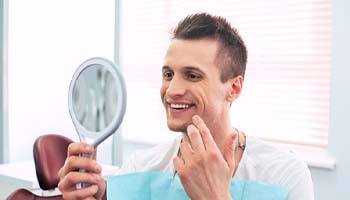 Man with dental implants in Brick Township smiling with mirror
