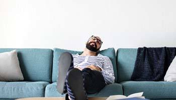 Man relaxing on couch after dental implant surgery in Brick Township