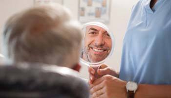 Man admiring his new dental implants in Brick Township in mirror