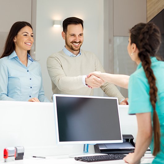 Man and woman checking in at dental office reception desk