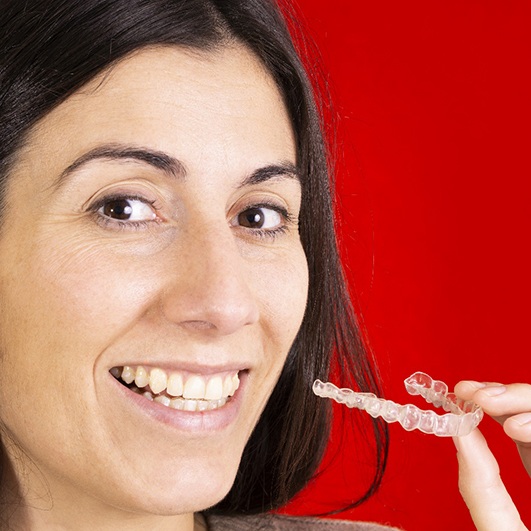 Woman holding Invisalign aligner