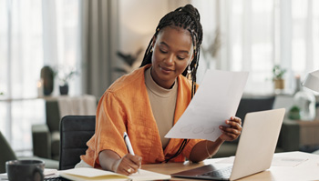 Closeup of woman taking notes at desk