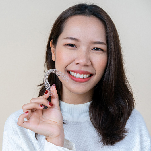 young woman holding Invisalign aligner 