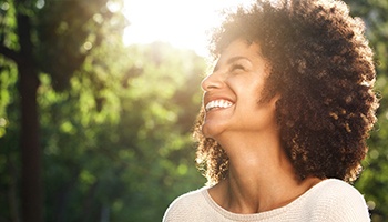 a person smiling and taking a walk in a park