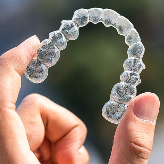 Hand holding an Invisalign tray