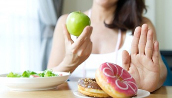 woman choosing to eat an apple instead of donuts 