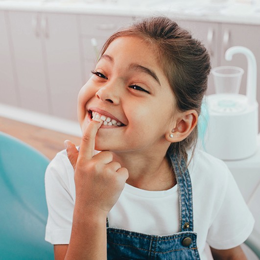 Little girl pointing to teeth during children's dentistry visit