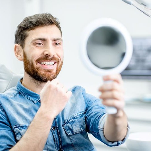 Dental patient looking in mirror after dental implant salvage