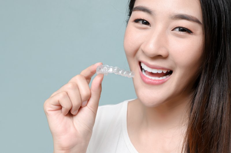 smiling person holding an Invisalign aligner tray
