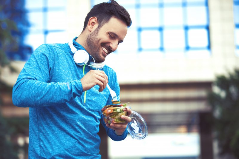 A man smiling as he eats well to help his dental implants