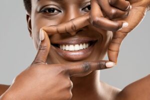 Woman using her fingers to frame beautiful white teeth 