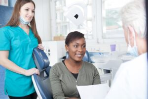 Patient speaking with dentist flanked by dental staff member.